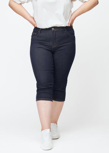 Tief dunkelblaue Denim-Capris für Damen in der Farbe Midnights mit Skinny-Passform, von vorne auf einem Plus-Size-Model gesehen.