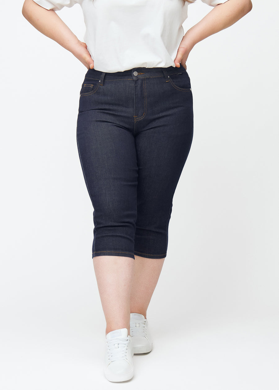 Tief dunkelblaue Denim-Capris für Damen in der Farbe Midnights mit Skinny-Passform, von vorne auf einem Plus-Size-Model gesehen.