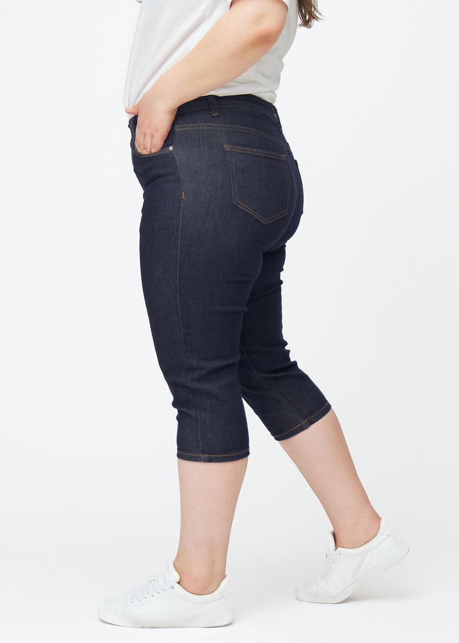 Tief dunkelblaue Denim-Capris für Damen in der Farbe Midnights mit Skinny-Passform, von der Seite auf einem Plus-Size-Model gesehen.