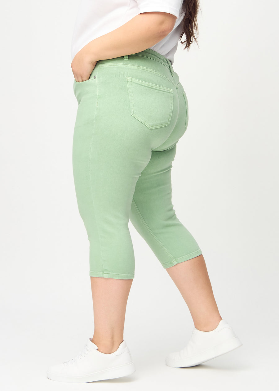 Skinny-Capris für Damen in pastellgrünem Jeansstoff, Farbe Mints. Seitenansicht an einem Plus-Size-Model, die figurbetonte Passform ist zu sehen.