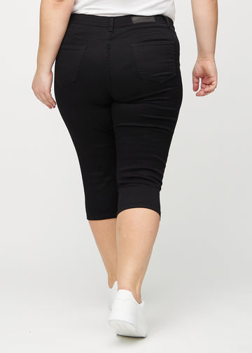 Skinny-Capris für Damen in schwarzem Jeansstoff, Farbe Ravens. Rückansicht an einem Plus-Size-Model, zeigt die Passform und Gesäßtaschen.