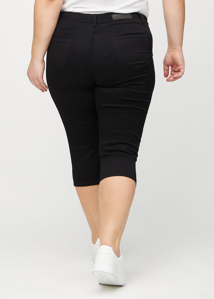 Skinny-Capris für Damen in schwarzem Jeansstoff, Farbe Ravens. Rückansicht an einem Plus-Size-Model, zeigt die Passform und Gesäßtaschen.