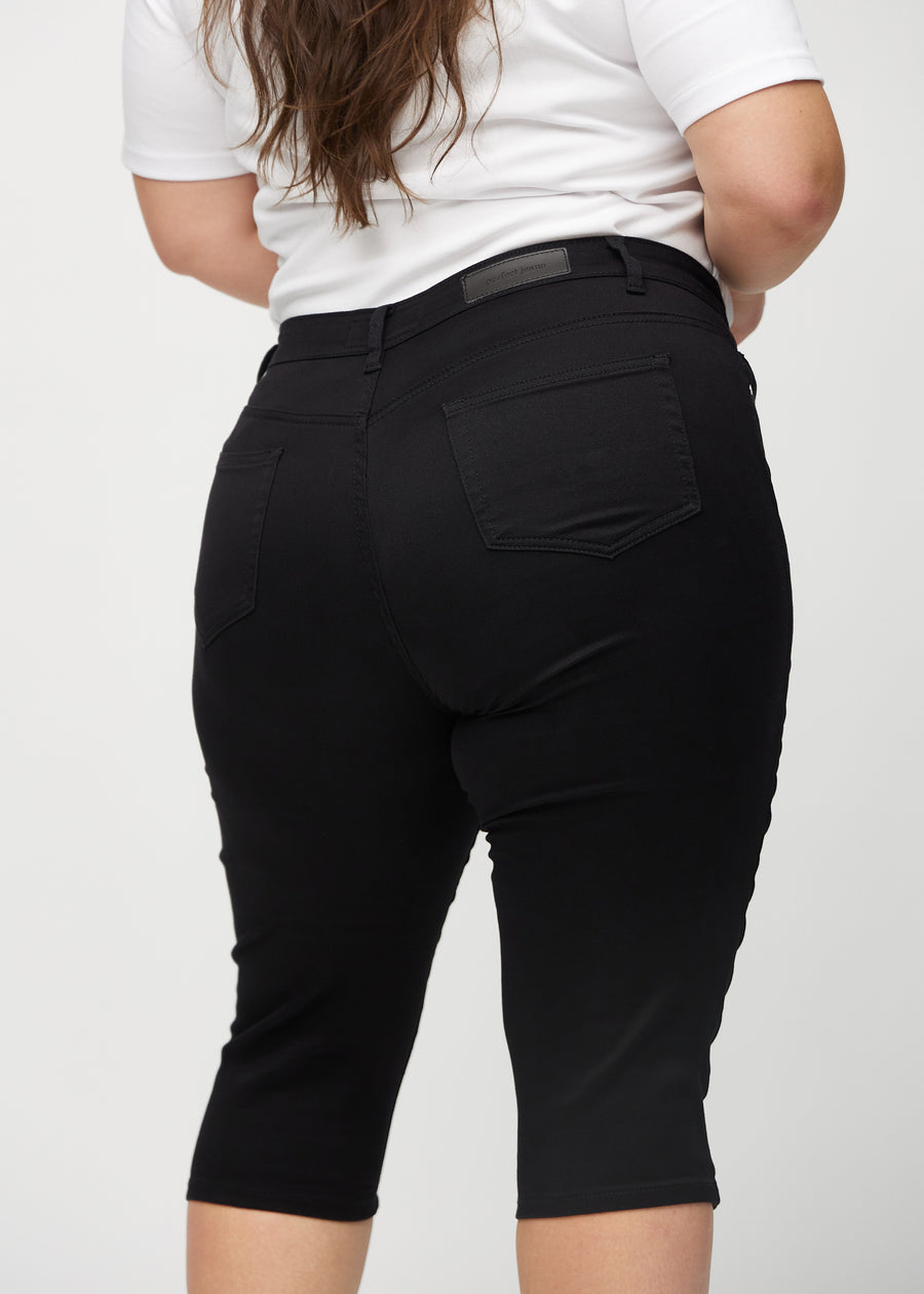 Skinny-Capris für Damen in schwarzem Jeansstoff, Farbe Ravens. Nahaufnahme von hinten an einem Plus-Size-Model, zeigt Taschen und Nähte.