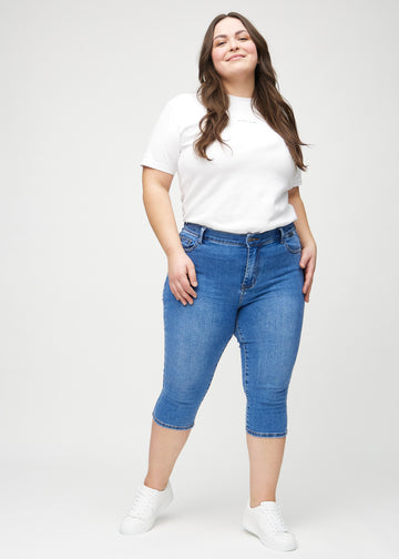 Skinny-Capris für Damen in blauem Denim, Farbe Rivers. Ganzkörperansicht eines Plus-Size-Models in den Capris.