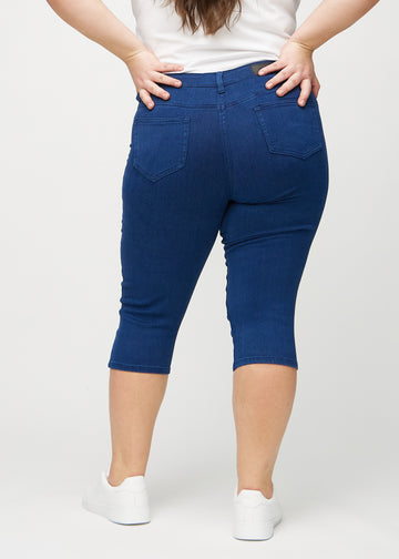 Dunkelblaue skinny Capris von hinten an einem Plus-Size-Model gesehen, sodass man das gesamte Produkt sehen kann.