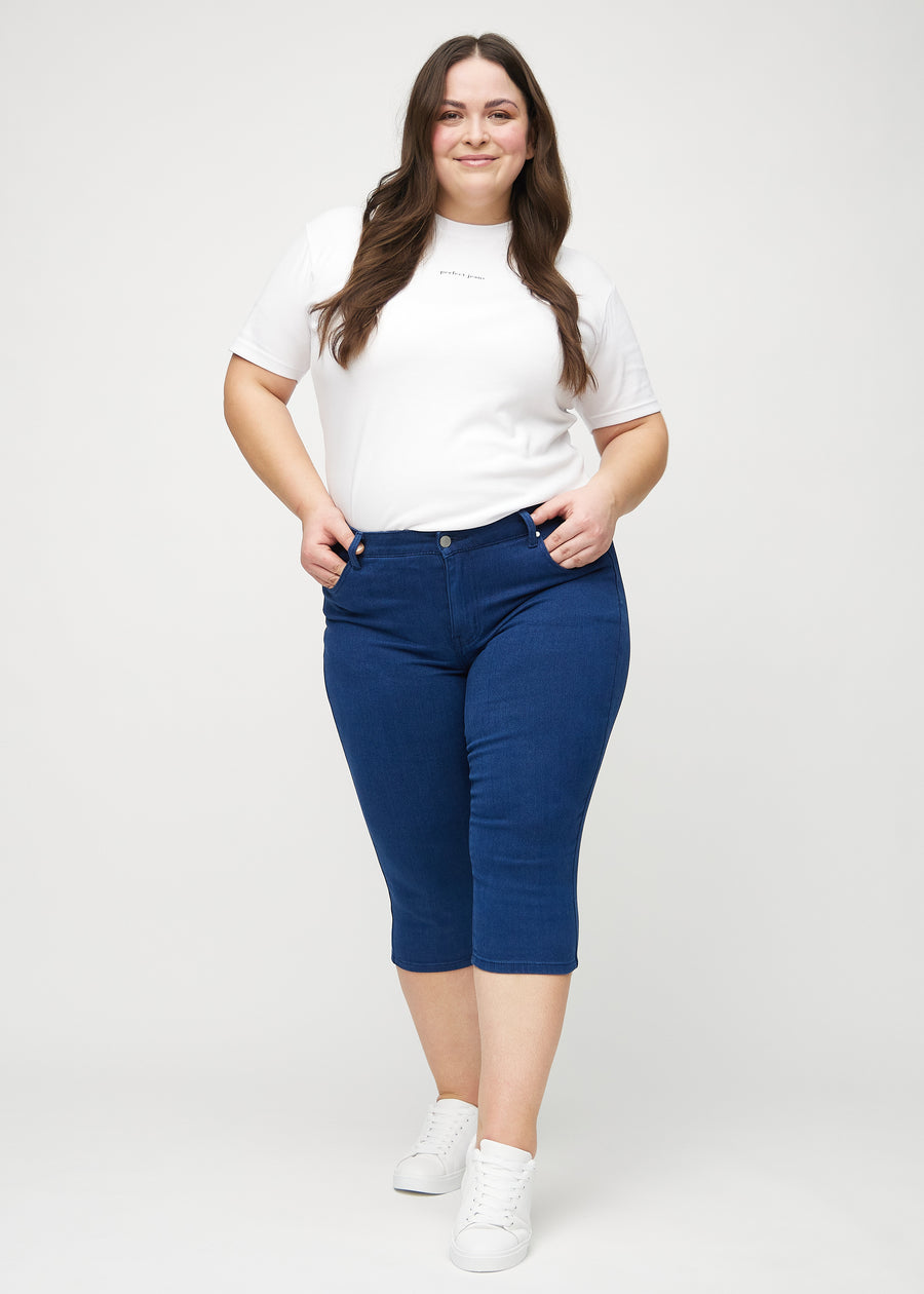 Ganzkörperbild eines Plus-Size-Models in dunkelblauen skinny Capris.