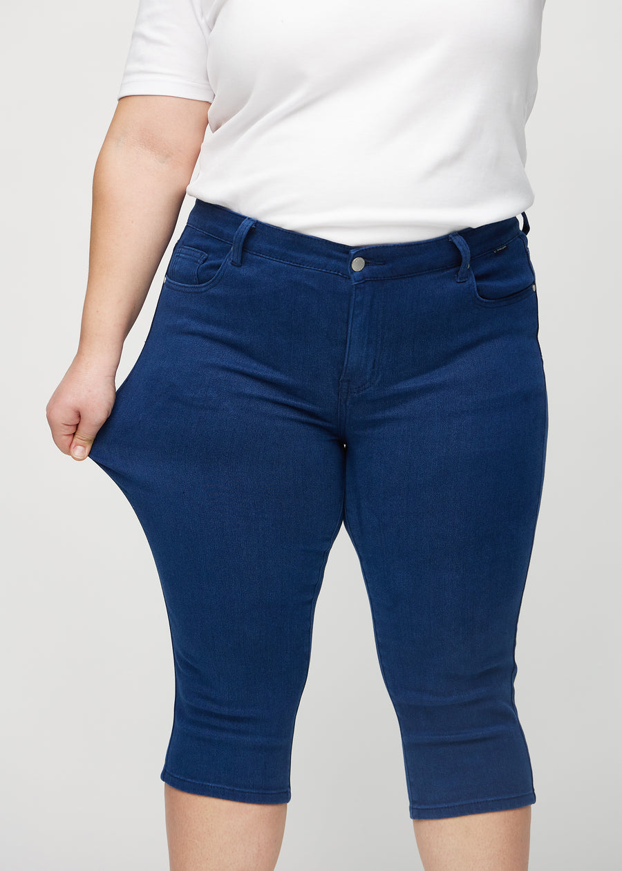 Das Plus-Size-Model zieht die Capris am Oberschenkel auseinander, um den Stretch zu zeigen.