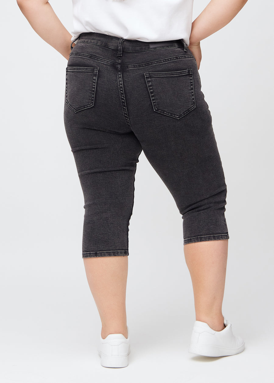 Skinny-Capris für Damen in dunkelgrauem Denim, Farbe Shadows. Rückansicht an einem Plus-Size-Model, zeigt die Passform und Gesäßtaschen.