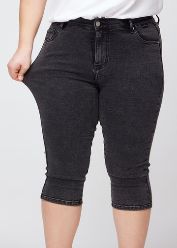 Skinny-Capris für Damen in dunkelgrauem Denim, Farbe Shadows. Ein Plus-Size-Model dehnt den Stoff, um den Stretch zu zeigen.