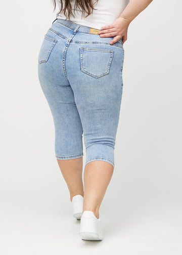 Hellblaue Denim-skinny-Capris von hinten an einem Plus-Size-Model gesehen, sodass man das gesamte Produkt sehen kann.