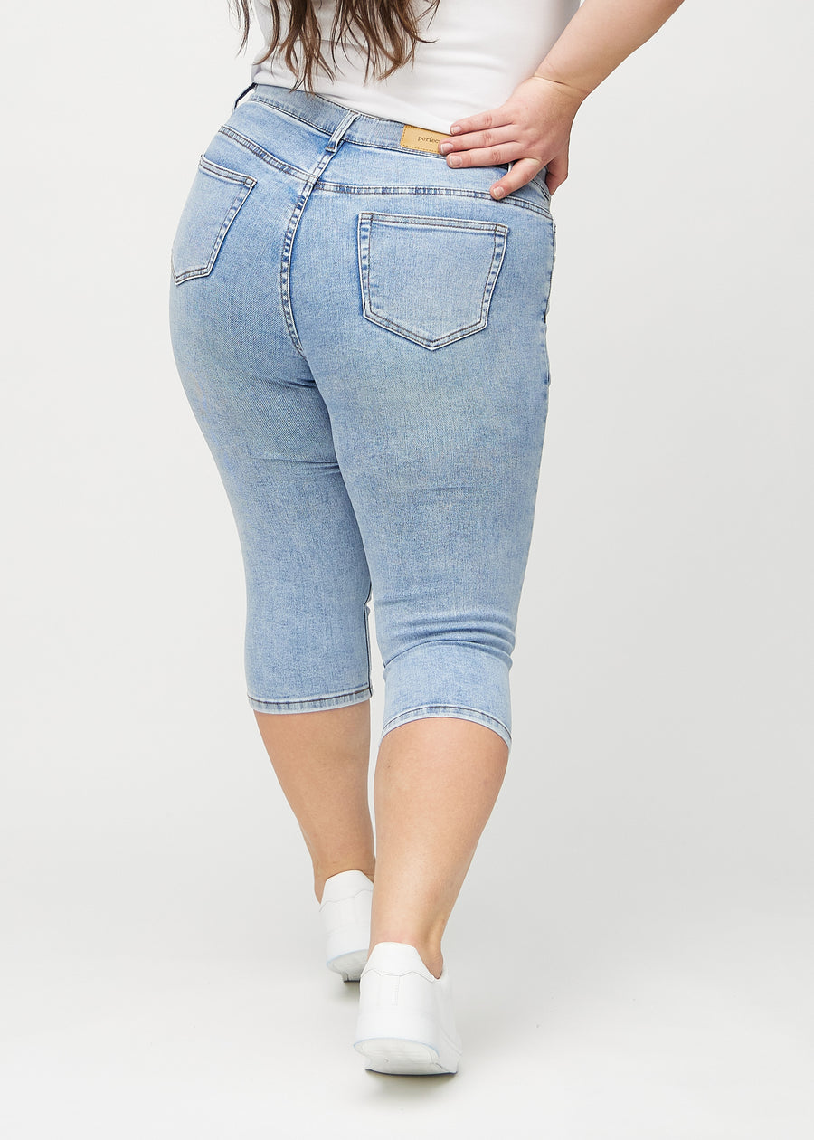 Hellblaue Denim-skinny-Capris von hinten an einem Plus-Size-Model gesehen, sodass man das gesamte Produkt sehen kann.