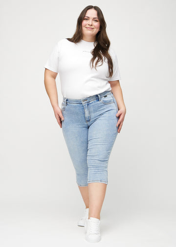 Ganzkörperbild eines Plus-Size-Models in hellblauen Denim-skinny-Capris.