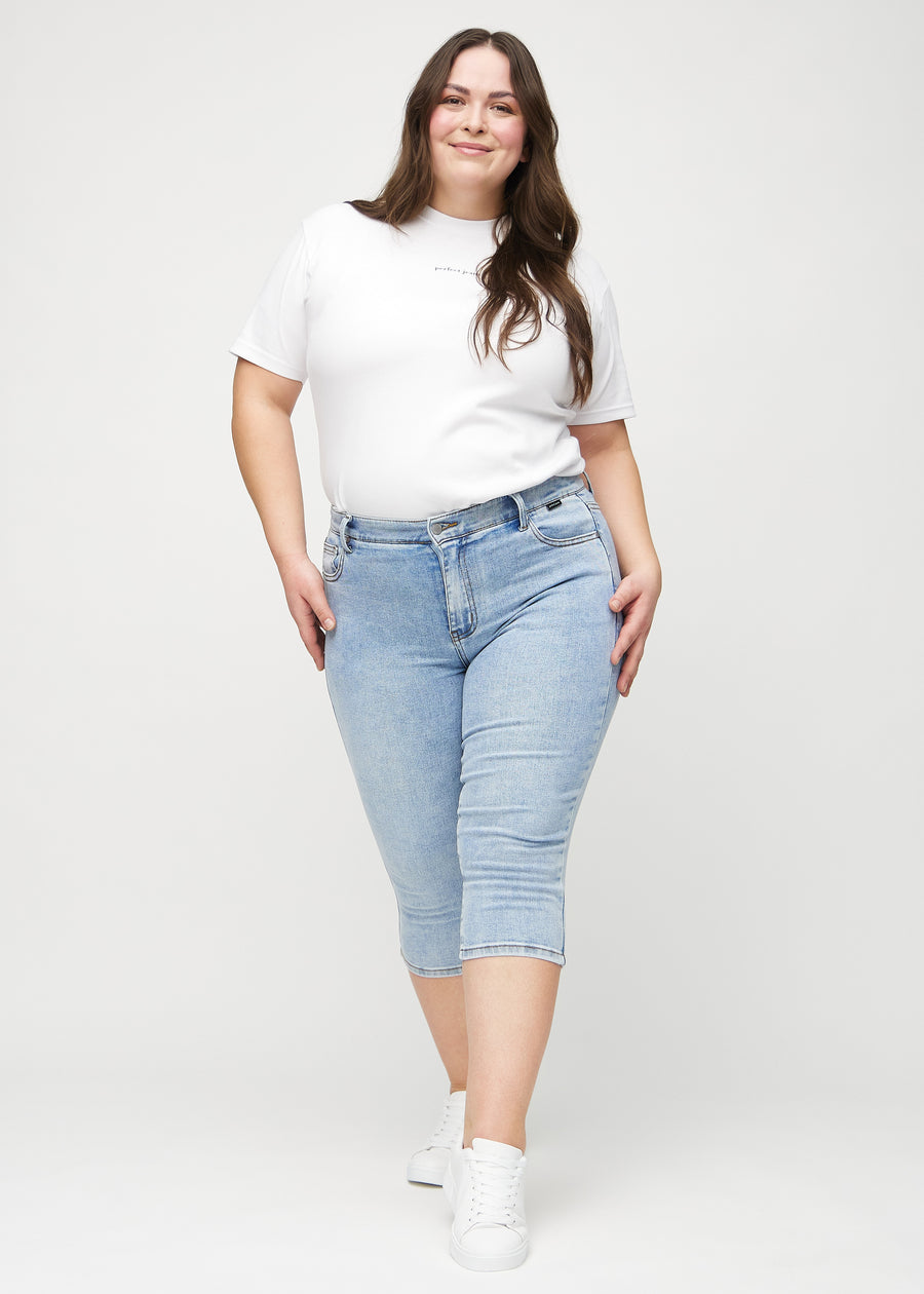 Ganzkörperbild eines Plus-Size-Models in hellblauen Denim-skinny-Capris.