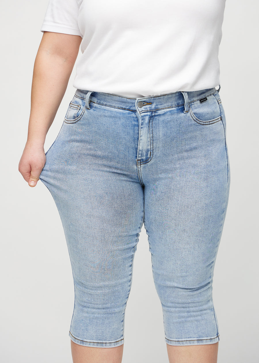 Ein Plus-Size-Model zieht die Capris am Oberschenkel auseinander, um den Stretch zu zeigen.