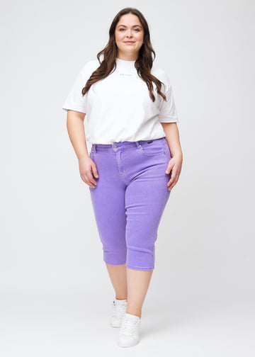 Slim-Capris für Damen aus pastellviolettem Jeansstoff, Farbe Lavenders. Ganzkörperansicht eines Plus-Size-Models in den Slim-Capris.