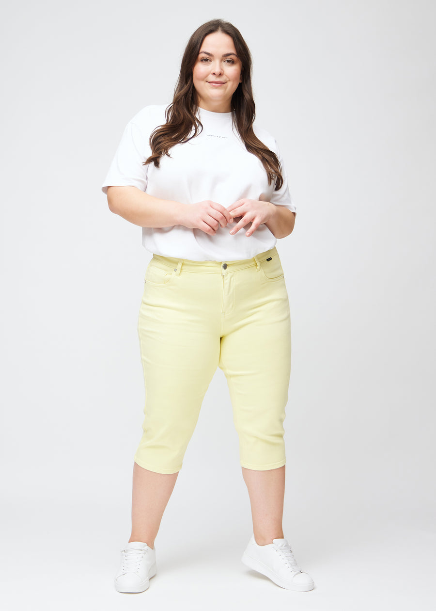 Ganzkörperbild eines Plus-Size-Models in hellgelben slim Capris.
