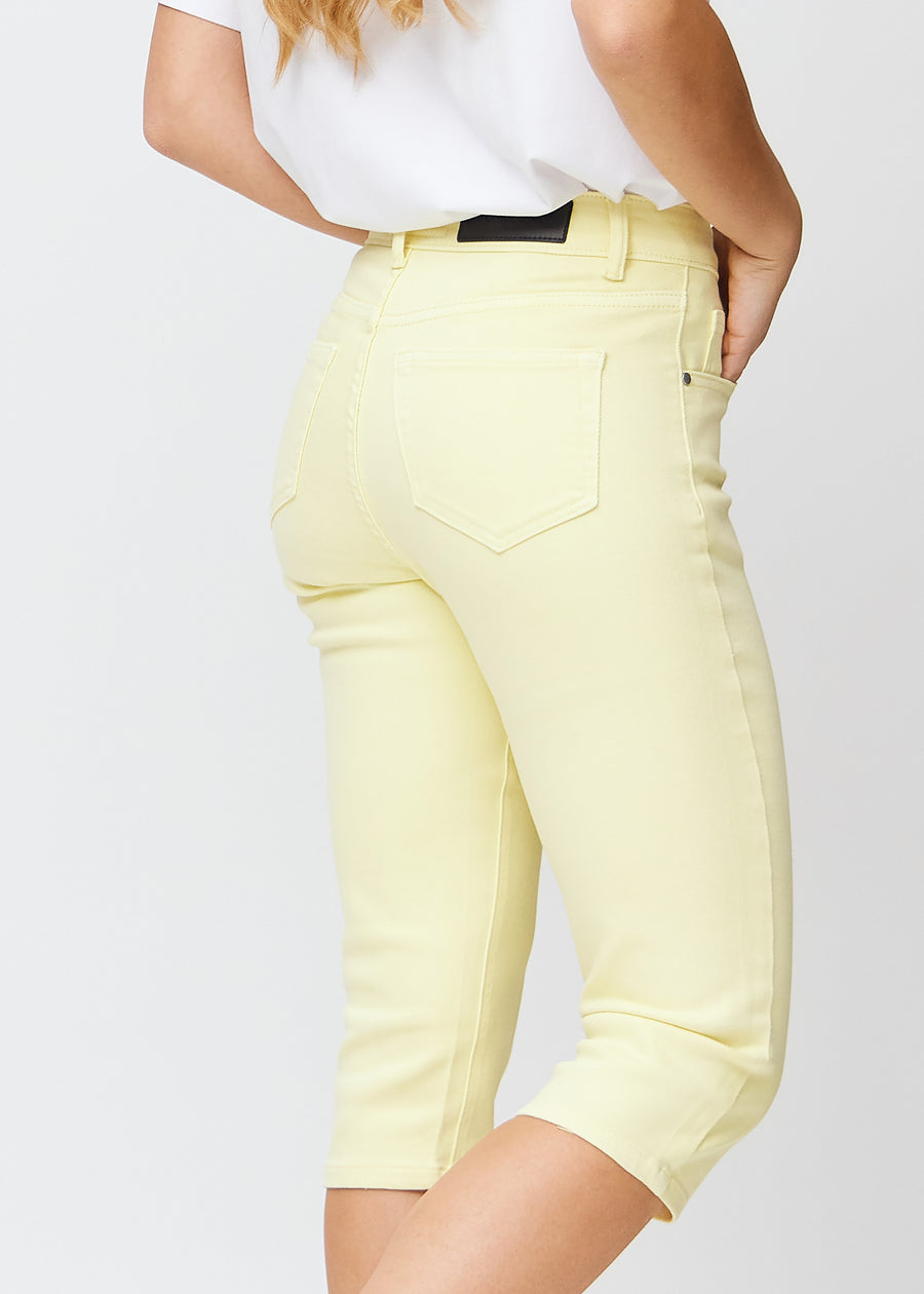 Hellgelbe slim Capris von hinten gesehen, das gesamte Produkt wird am Model mit Fokus auf Passform und Länge gezeigt.