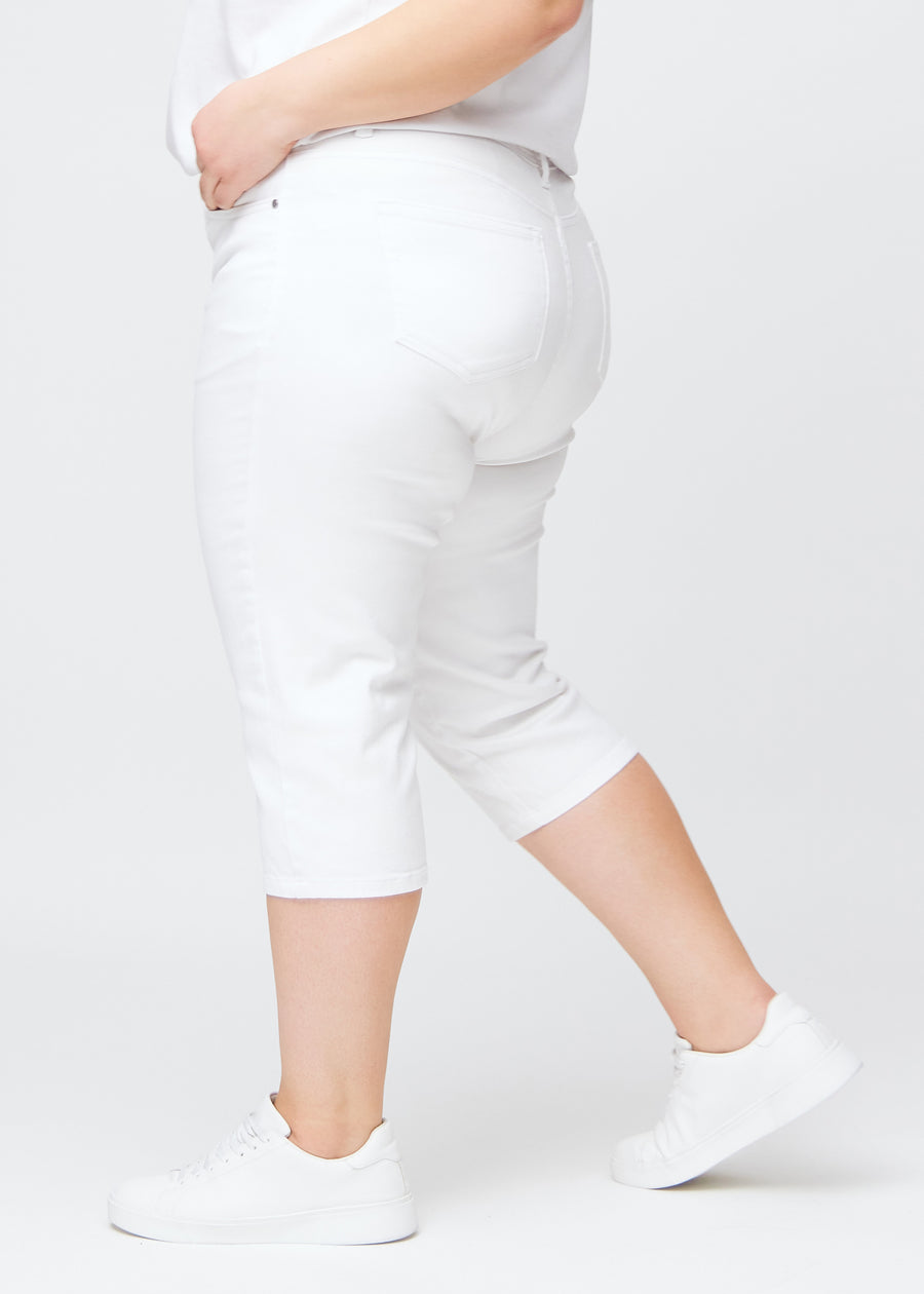 Slim-Capris für Damen aus weißem Jeansstoff, Farbe Marguerites. Seitenansicht an einem Plus-Size-Model, figurbetonter Schnitt und mittelhoher Bund (Mid Rise).