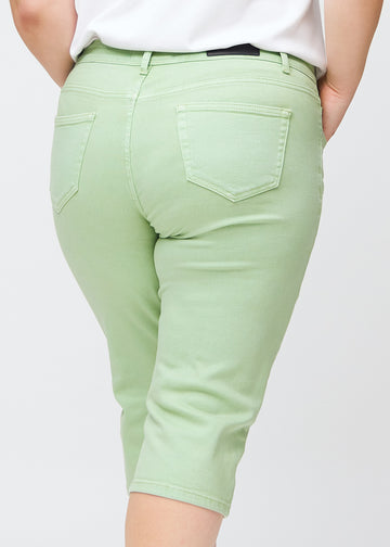 Slim-Capris für Damen aus pastellhellgrünem Jeansstoff, Farbe Mints. Nahaufnahme von hinten an einem Plus-Size-Model, zeigt Taschen und Nähte.