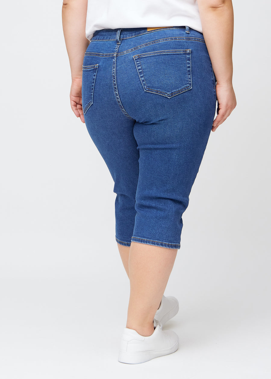 Dunkelblaue Denim-slim-Capris von hinten an einem Plus-Size-Model gesehen, deutliches Bild des gesamten Produkts und der Taschen.