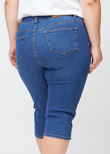 Nahaufnahme des Gesäßbereichs eines Plus-Size-Models in dunkelblauen Denim-slim-Capris, Detailfokus auf Taschen und Nähte.