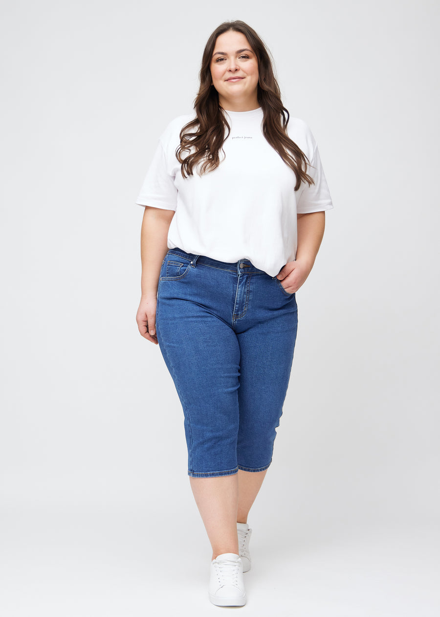 Ganzkörperbild eines Plus-Size-Models in dunkelblauen Denim-slim-Capris.