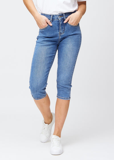 Slim-Capris für Damen aus blauem Denim, Farbe Rivers. Vorderansicht an einem Model, figurbetonter Schnitt bis knapp unter das Knie.