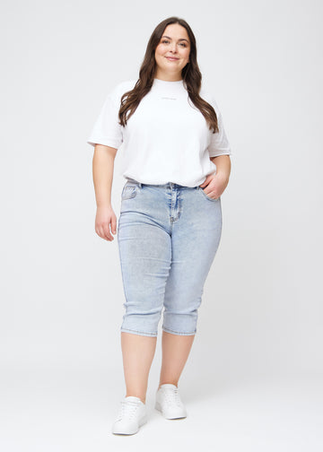 Slim-Capris für Damen aus hellblauem Denim, Farbe Waves. Ganzkörperansicht eines Plus-Size-Models in den Slim-Capris.