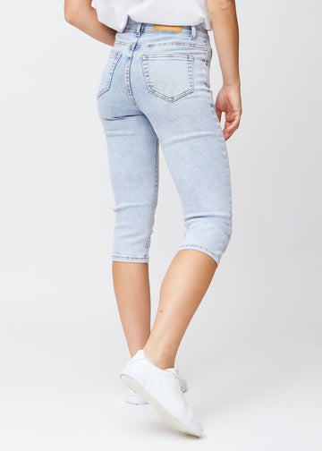Slim-Capris für Damen aus hellblauem Denim, Farbe Waves. Rückansicht an einem Model, zeigt Passform, Länge und Gesäßtaschen.