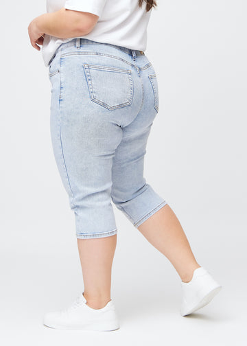 Slim-Capris für Damen aus hellblauem Denim, Farbe Waves. Seitenansicht an einem Plus-Size-Model, figurbetonter Schnitt und mittelhoher Bund (Mid Rise).