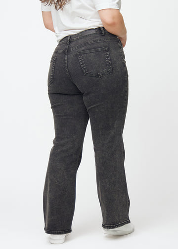 Dunkelgraue Mid-Rise-Bootcut-Jeans in der Farbe Shadows. Rückansicht an einem Plus-Size-Model, die gesamte Passform ist zu sehen.