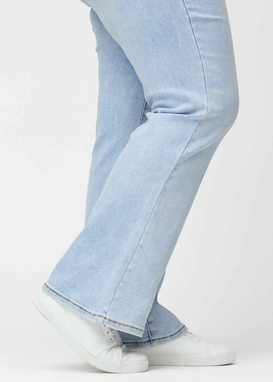 Hellblaue Mid-Rise-Bootcut-Jeans in der Farbe Waves. Nahaufnahme am Knöchel eines Plus-Size-Model, um den leichten Schlag am Beinabschluss zu zeigen.