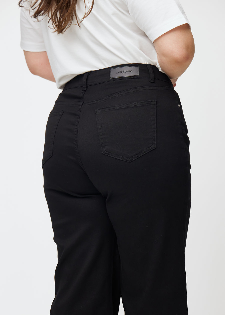 Schwarze hochtaillierte jeans, die an der Taille eng anliegen und eine lockere Passform mit Weite nach unten haben, nah von hinten an einem Plus-Size-Model gesehen, um Details zu zeigen.