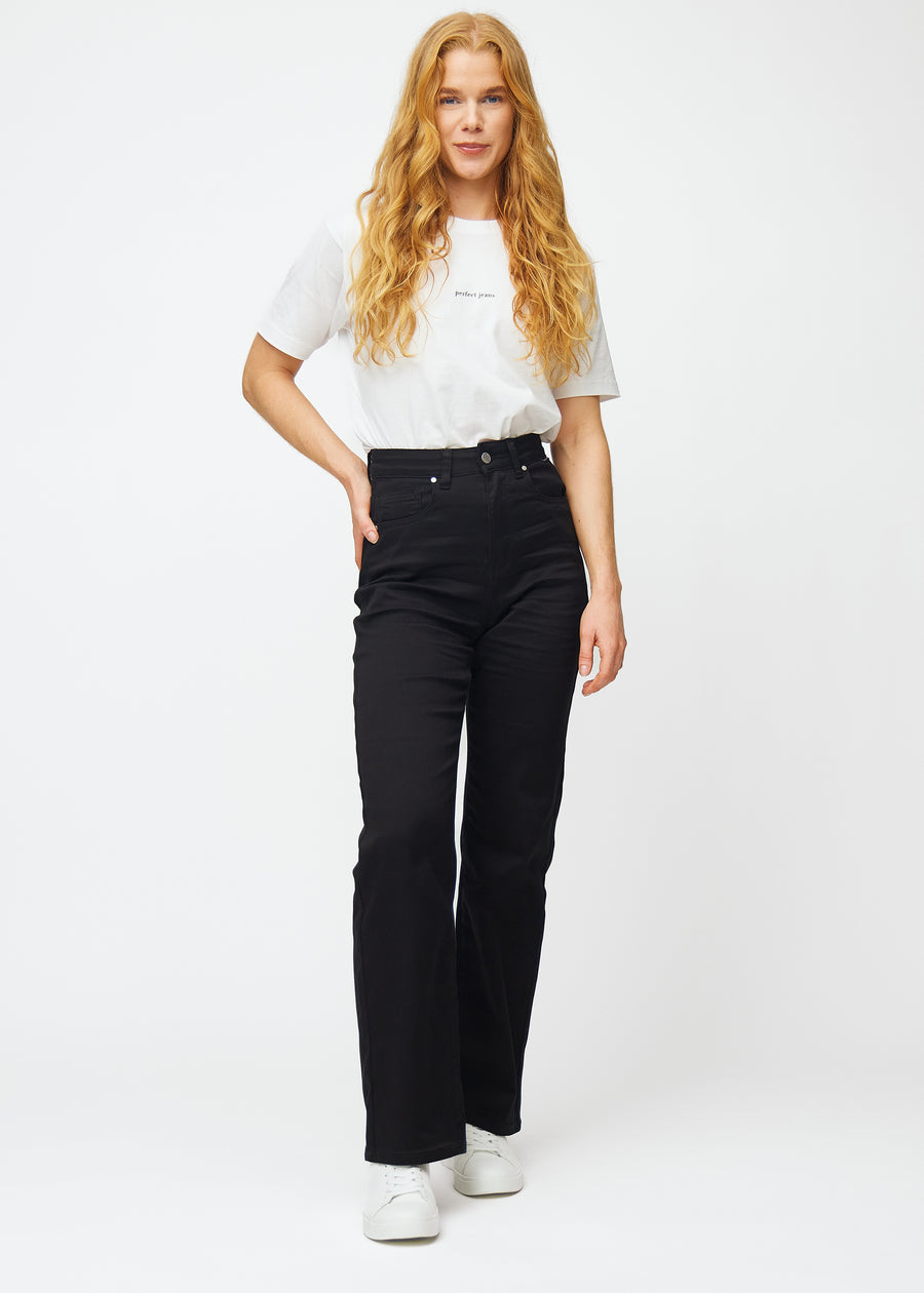 Ein Ganzkörperbild eines Models in schwarzen hochtaillierten jeans, die an der Taille eng anliegen und eine lockere Passform mit Weite nach unten haben.