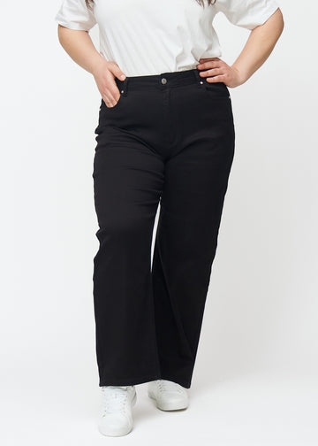 Schwarze hochtaillierte jeans des Modells Ravens, die an der Taille eng anliegen und eine lockere Passform mit Weite nach unten haben, an einem Plus-Size-Model von vorne gesehen.