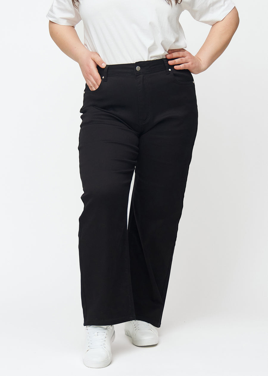 Schwarze hochtaillierte jeans des Modells Ravens, die an der Taille eng anliegen und eine lockere Passform mit Weite nach unten haben, an einem Plus-Size-Model von vorne gesehen.