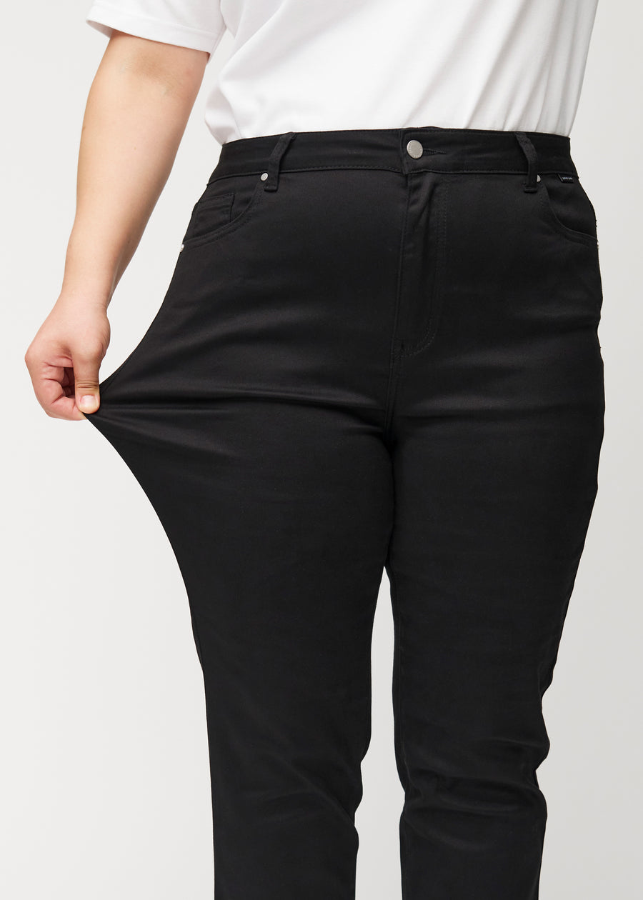 Das Plus-Size-Model zieht die Jeans am Oberschenkel auseinander, um den Stretch zu zeigen.