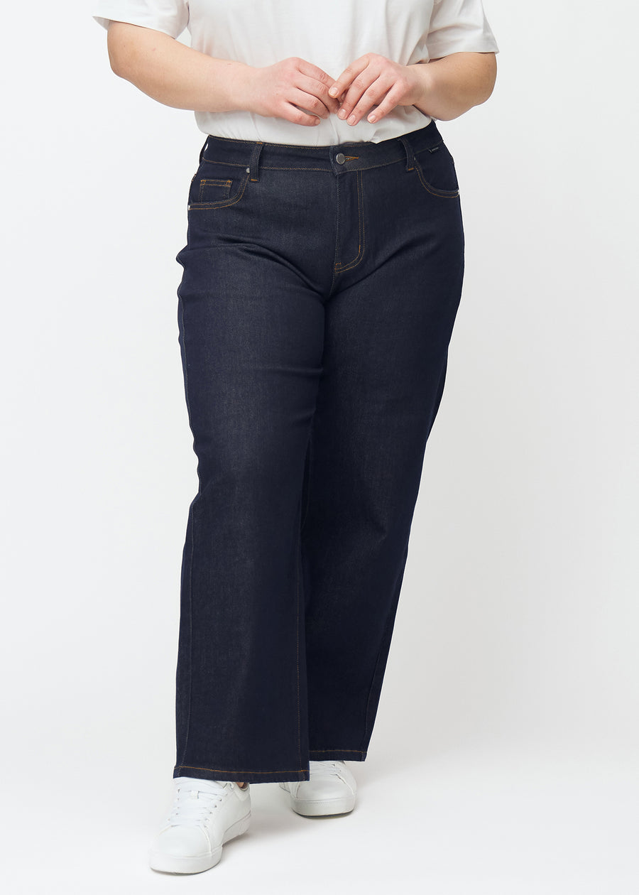 Tief dunkelblaue Denim jeans für Damen in der Farbe Midnights mit loose Passform, von vorn an einem Plus-Size-Model gezeigt.