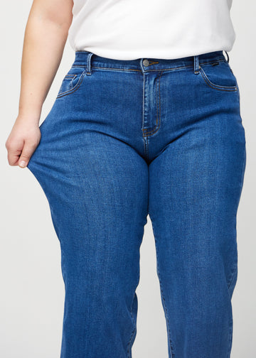 Loose-Jeans für Damen in Dunkelblau, Farbe Oceans. Ein Plus-Size-Model dehnt den Jeansstoff am Oberschenkel, um den Stretch zu zeigen.
