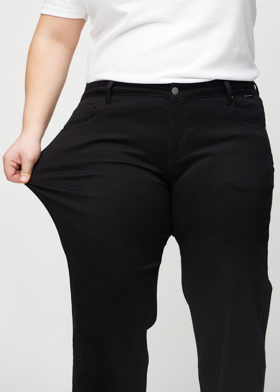 Loose-Jeans für Damen in Schwarz, Farbe Ravens. Ein Plus-Size-Model dehnt den Jeansstoff am Oberschenkel, um den Stretch zu zeigen.