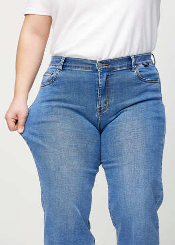 Das Plus-Size-Model zieht die Jeans am Oberschenkel, um den Stretch zu zeigen.