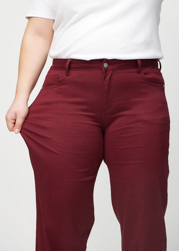 Loose-Jeans für Damen in Dunkelrot, Farbe Santas. Ein Plus-Size-Model dehnt den Jeansstoff am Oberschenkel, um den Stretch zu zeigen.