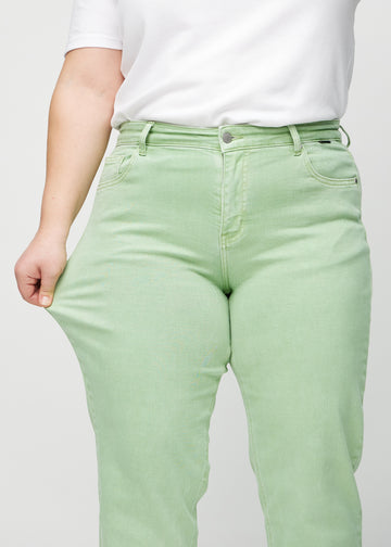 Das Plus-Size-Model zieht die Jeans am Oberschenkel auseinander, um den Stretch zu zeigen.