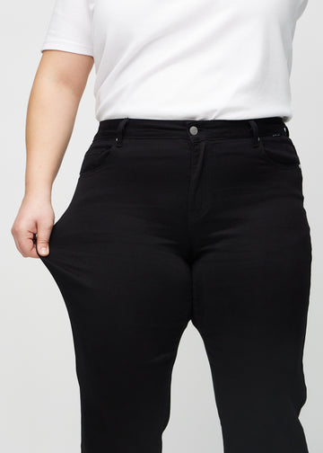 Regular-Jeans für Damen in Schwarz, Farbe Ravens. Ein Plus-Size-Model dehnt den Stoff am Oberschenkel, um den Stretch zu zeigen.