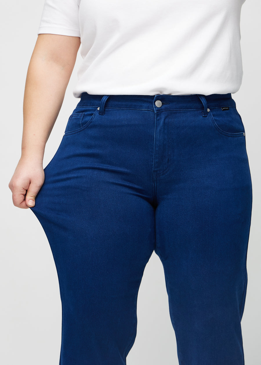 Regular-Jeans für Damen in Dunkelblau, Farbe Royals. Ein Plus-Size-Model dehnt den Stoff am Oberschenkel, um den Stretch zu zeigen.