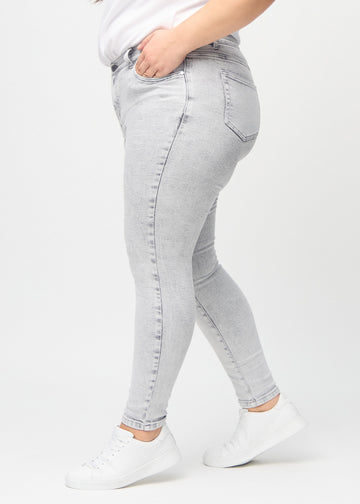 Hellgrauer Denim skinny jeans von der Seite an einem Plus-Size-Model gezeigt.