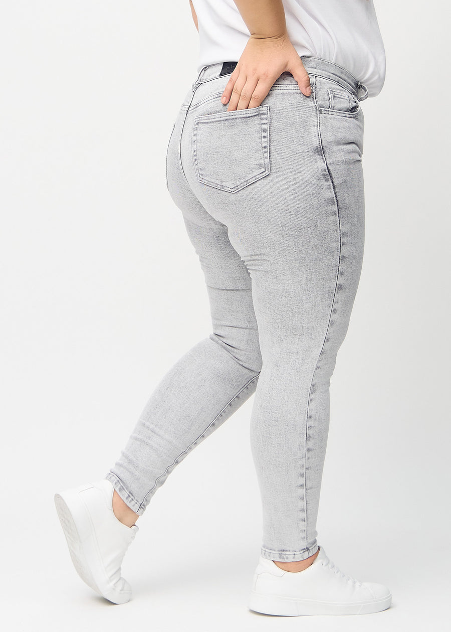 Hellgrauer Denim skinny jeans von hinten an einem Plus-Size-Model gezeigt, sodass man das gesamte Produkt sehen kann.