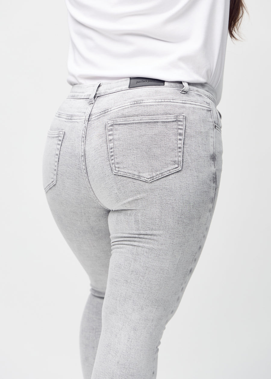 Hellgrauer Denim skinny jeans von hinten aus der Nähe an einem Plus-Size-Model gezeigt, um Details zu zeigen.