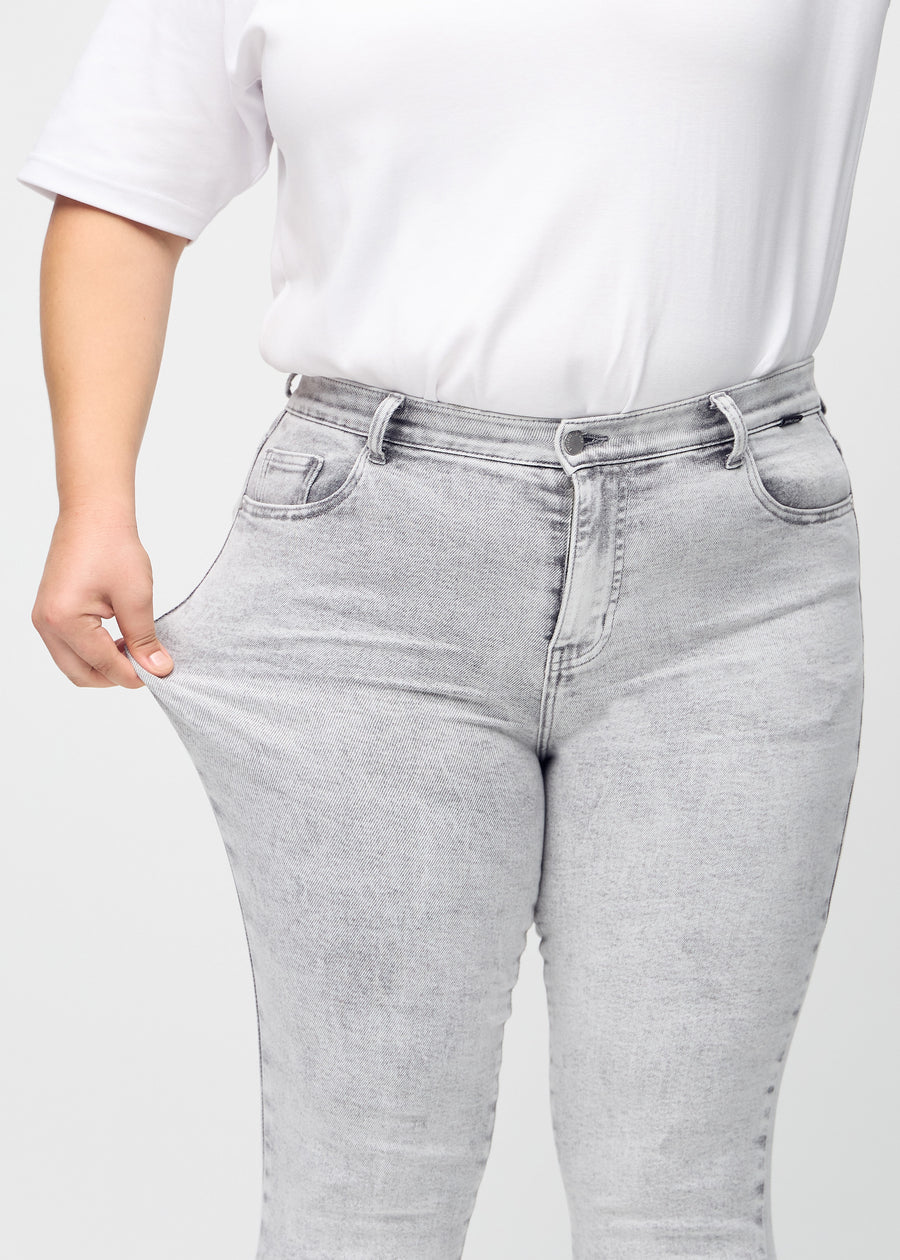 Das Plus-Size-Model zieht die Jeans am Oberschenkel auseinander, um den Stretch zu zeigen
