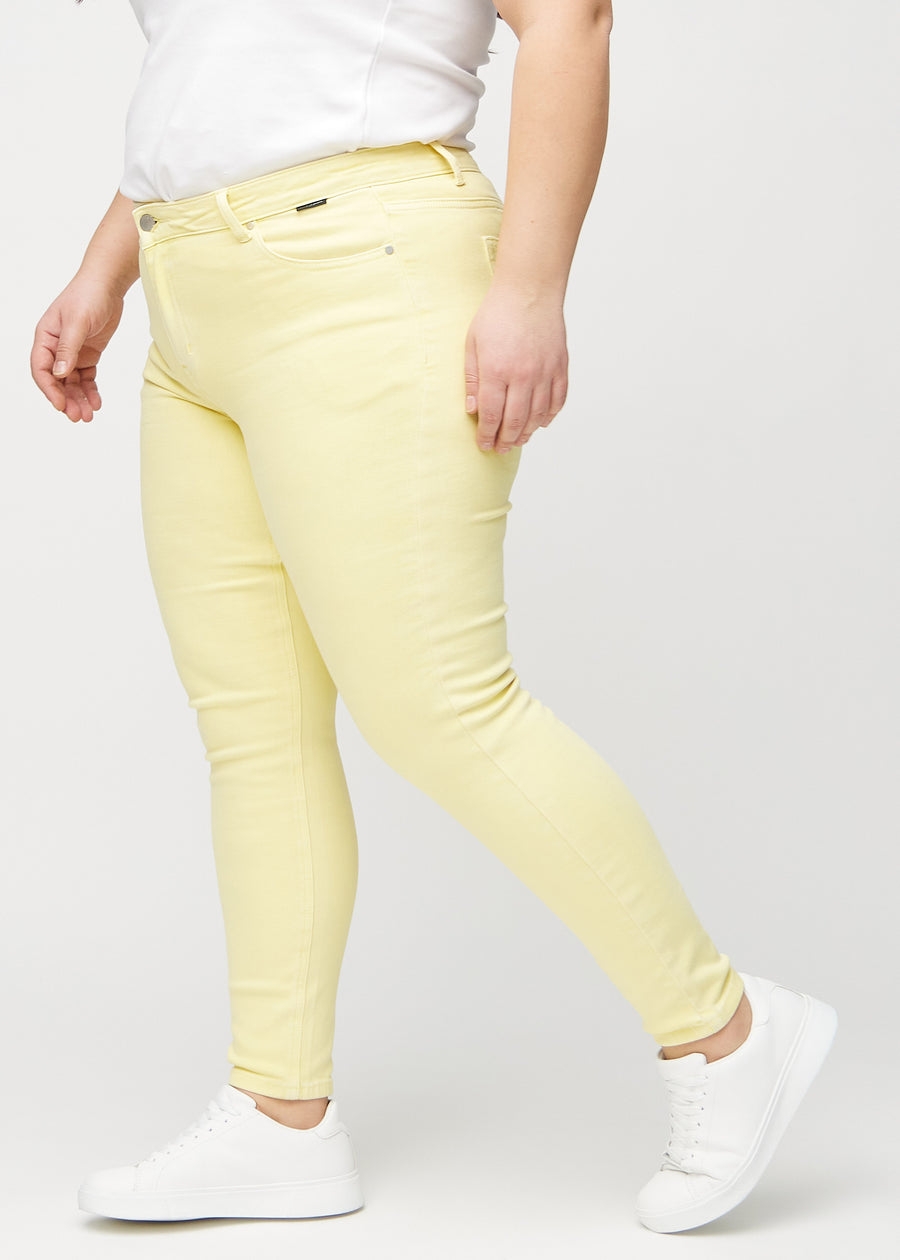 Hellgelbe skinny jeans von der Seite an einem Plus-Size-Model gesehen.